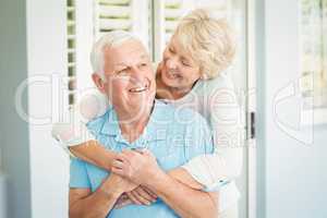 Portrait of senior couple smiling while hugging at home
