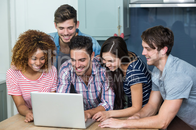 Multi-ethnic young friends looking in laptop on table