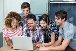 Multi-ethnic young friends looking in laptop on table