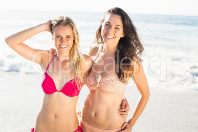 Portrait of two happy women in bikini standing on the beach