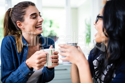 Beautiful female friends laughing while drinking coffee