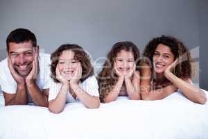 Portrait of happy family lying on bed