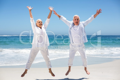 Senior couple jumping with raised arms