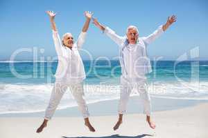 Senior couple jumping with raised arms