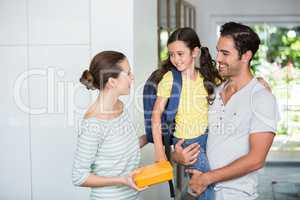 Mother holding lunch box with father carrying daughter