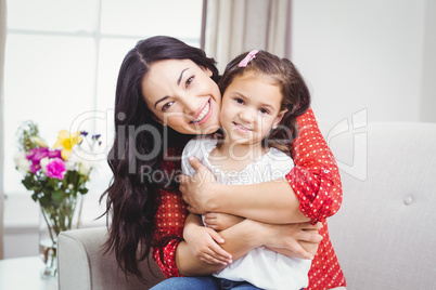 Happy mother embracing daughter at home