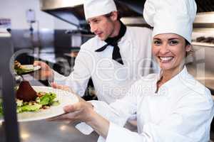 Chefs handing dinner plates through order station