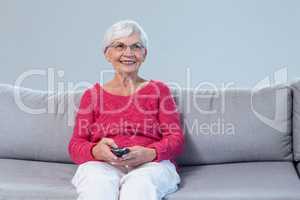 Senior woman sitting and watching television at home