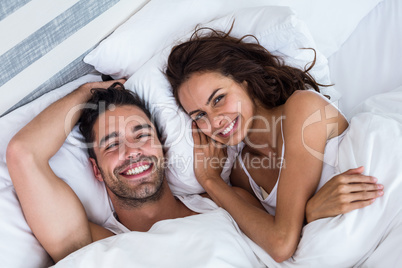 High angle portrait of cheerful couple relaxing on bed