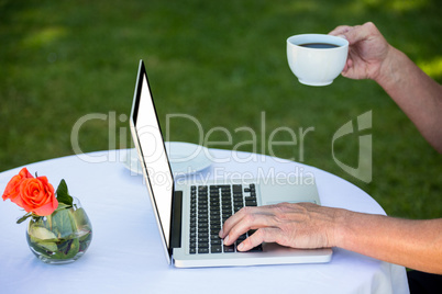 Casual businessman using laptop and having coffee