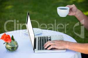 Casual businessman using laptop and having coffee