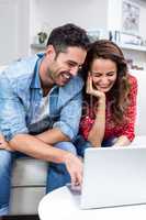 Cheerful couple using laptop