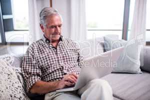 Senior man using laptop in living room