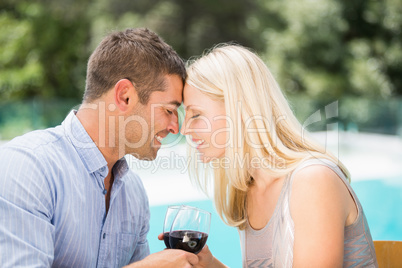 Smiling couple with eyes closed while toasting red wine