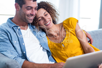 Young couple sitting on sofa and using laptop