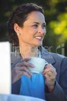 Smiling businesswoman drinking coffee with laptop