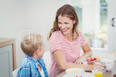 Mother and son smiling while having breakfast