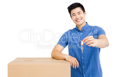 Young man leaning on cardboard box and holding a key