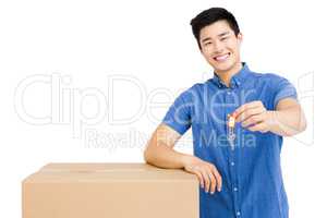 Young man leaning on cardboard box and holding a key
