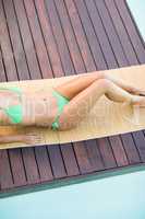 Woman in green bikini relaxing by pool side