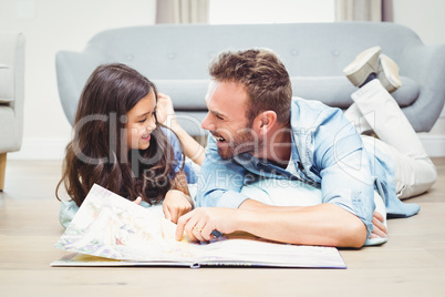 Daughter and father with picture book lying on floor