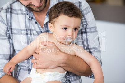 Father carrying son having pacifier in mouth