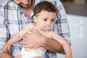Father carrying son having pacifier in mouth