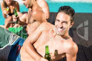 Young man having beer at the swimming pool