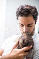 Father kissing baby while standing