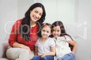 Portrait of smiling mother and daughters at home