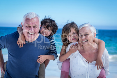 Happy grandparents giving piggy back to children