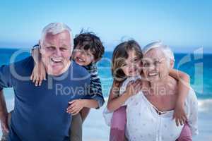 Happy grandparents giving piggy back to children