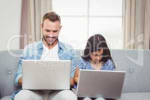 Father and daughter using laptop at home