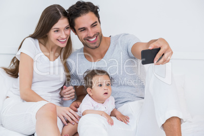Happy family clicking selfie on bed
