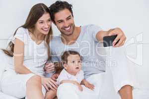 Happy family clicking selfie on bed