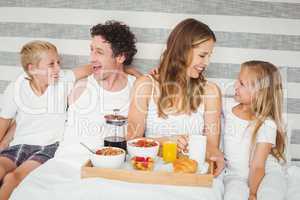Happy family enjoying breakfast on bed