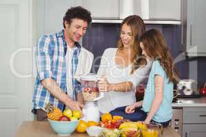 Parents and daughter preparing fruit juice