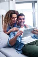 Happy couple using a digital tablet on sofa