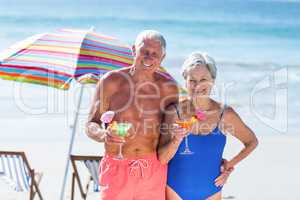 Cute mature couple having cocktails on the beach