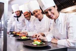 Smiling chef while decorating food plate