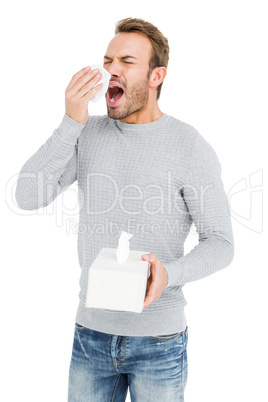 Young man holding a tissue and sneezing