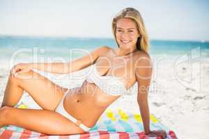 Smiling woman sitting on a towel at the beach