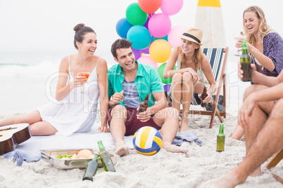 Group of friends with drinks having fun together on the beach