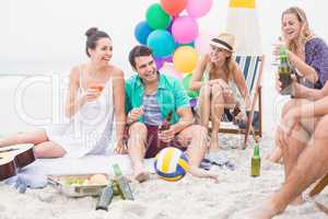 Group of friends with drinks having fun together on the beach