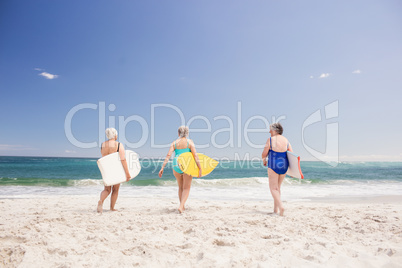 Senior woman friends holding surfboard