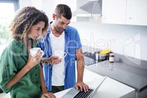 Couple using laptop while having a cup of coffee