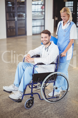 Portrait of smiling doctor sitting on wheelchair with female col