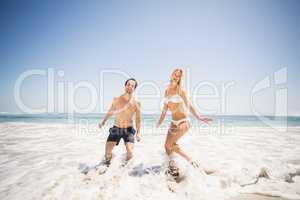 Happy couple having fun in water on shore