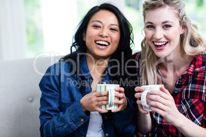 Cheerful young female friends with coffee cup