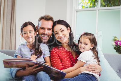 Portrait of happy family with picture book on sofa